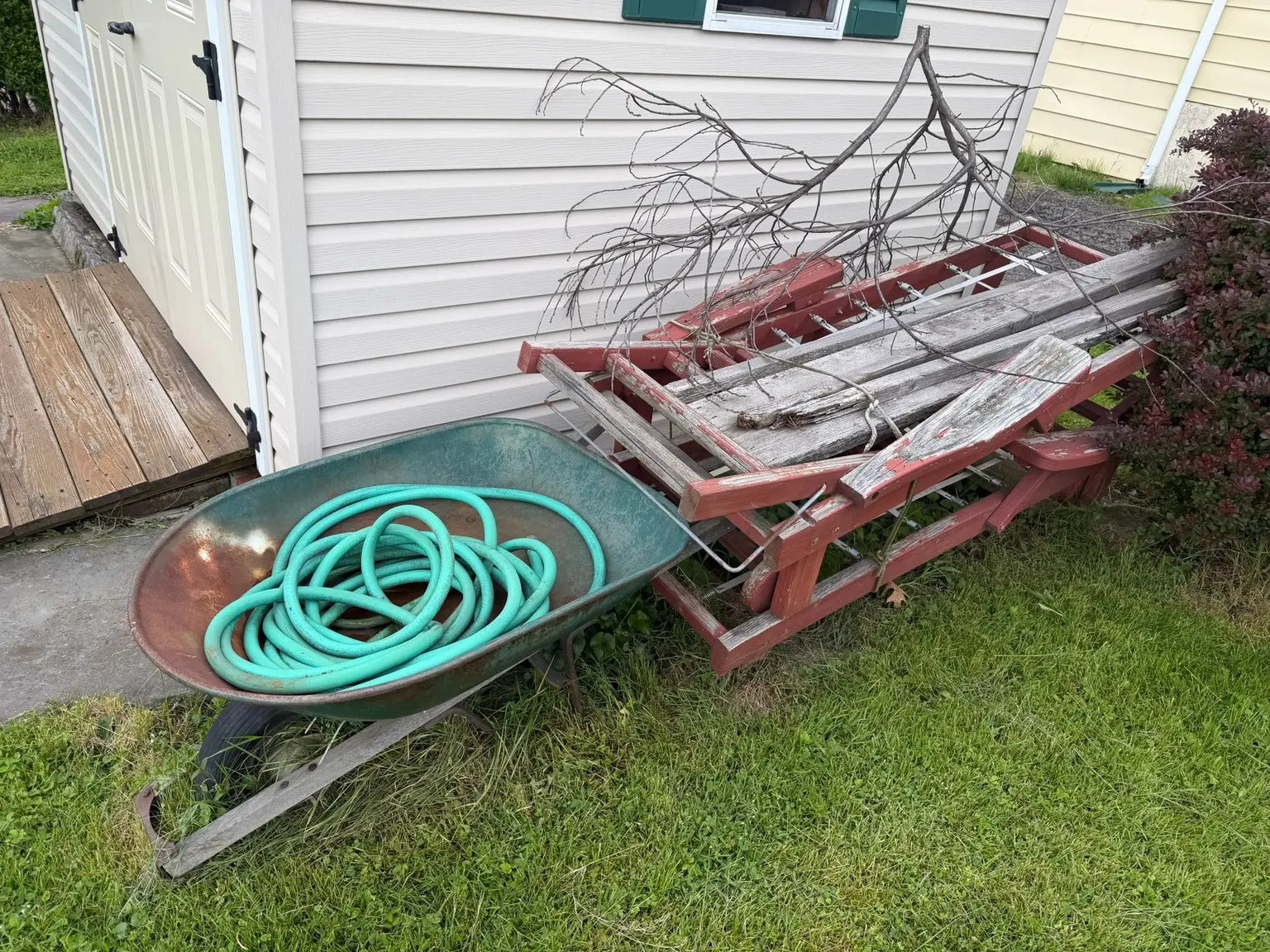 Wheelbarrow, old wood and outdoor debris ready for removal