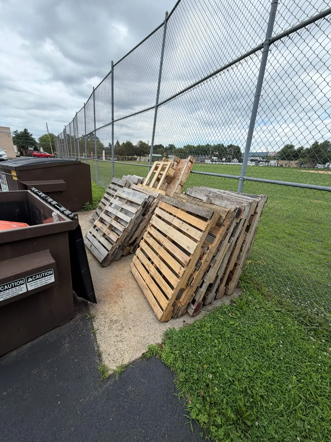 Wood pallets staged beside commercial dumpsters for pickup