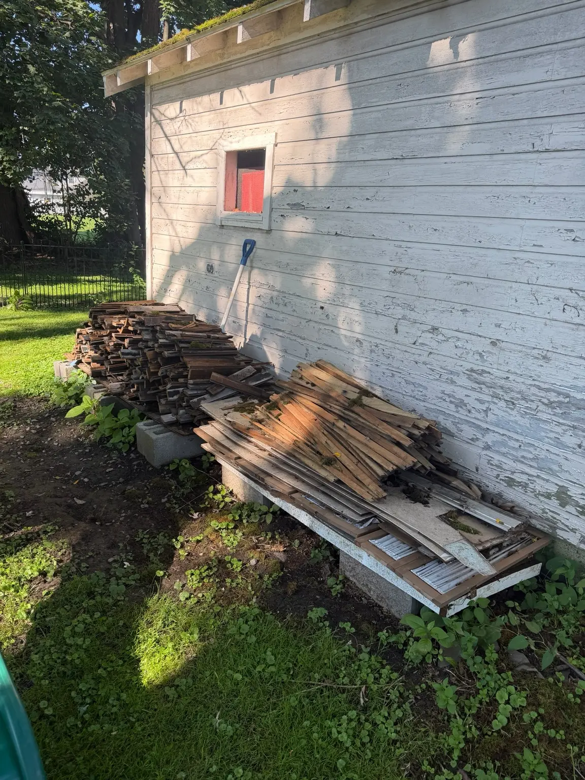 Removed wood flooring stacked beside a garage for haul-away