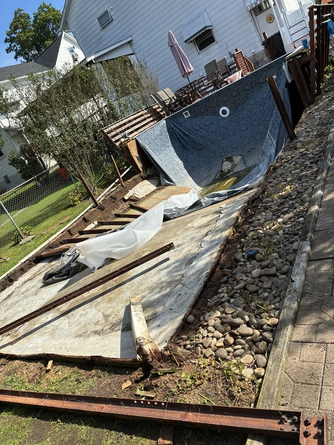 Wooden pool demolition underway with the liner and plywood exposed