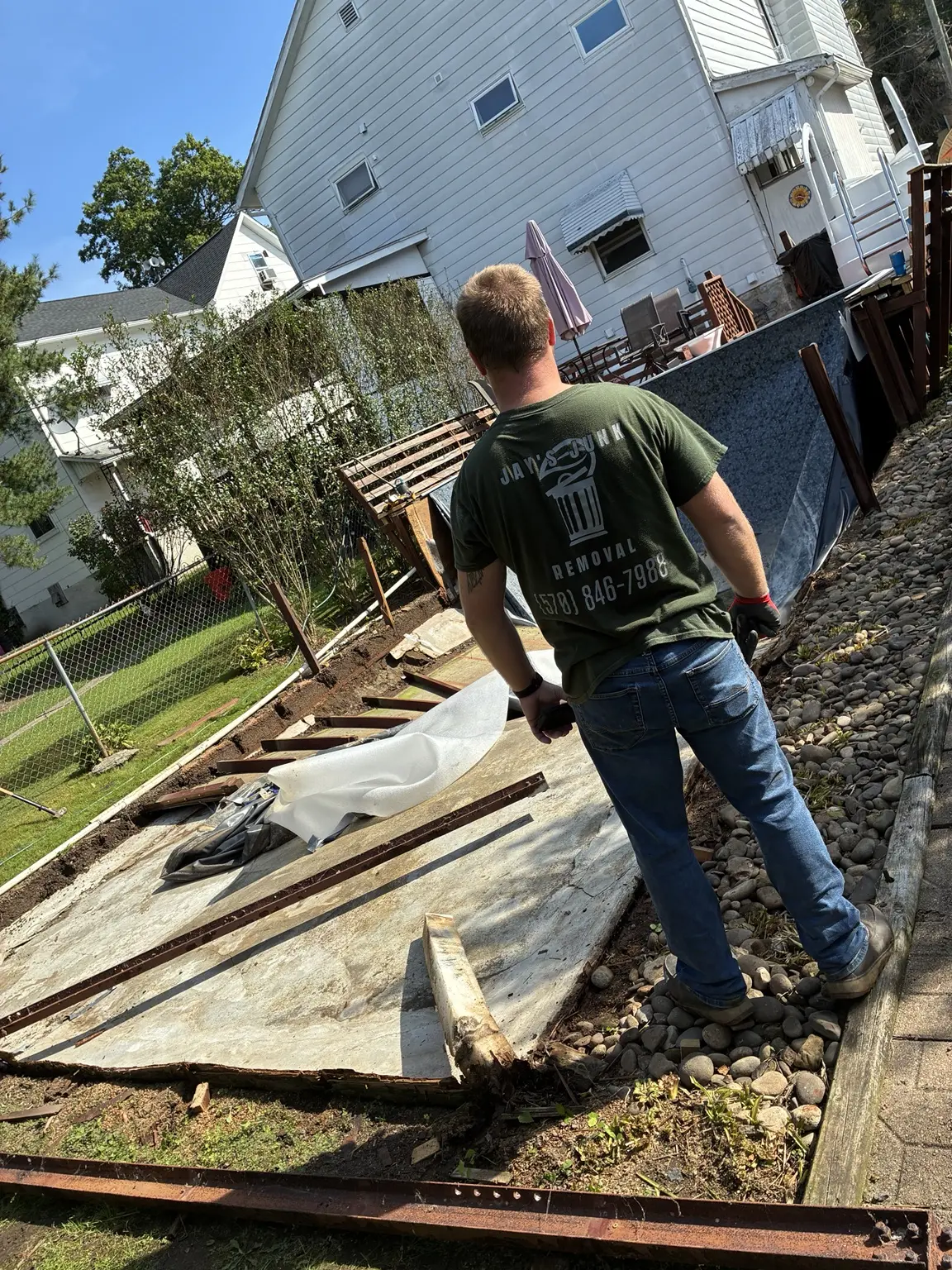 Jay's Junk Removal crew member working beside the demolished pool