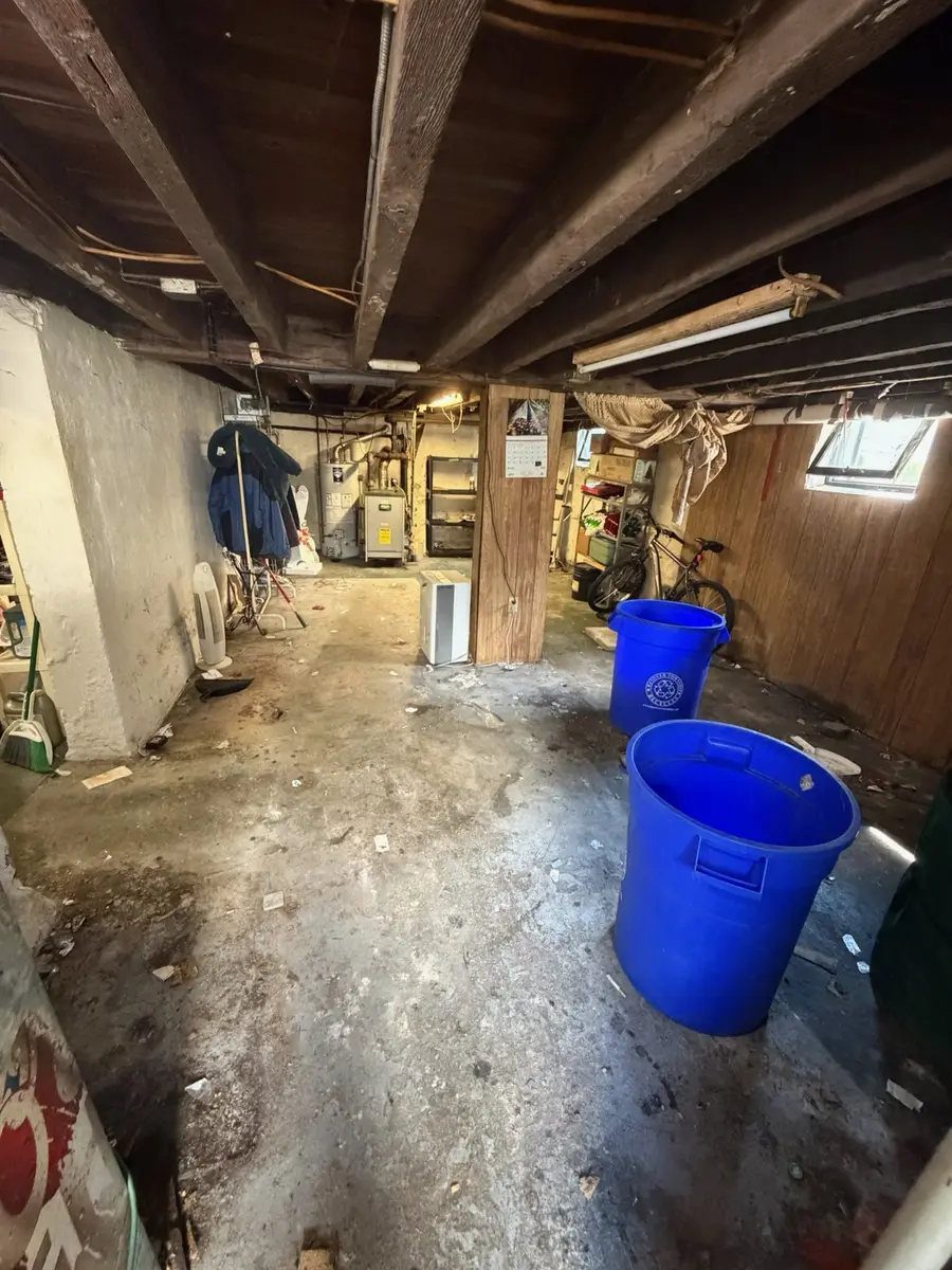 Cleared basement with two blue recycling cans remaining