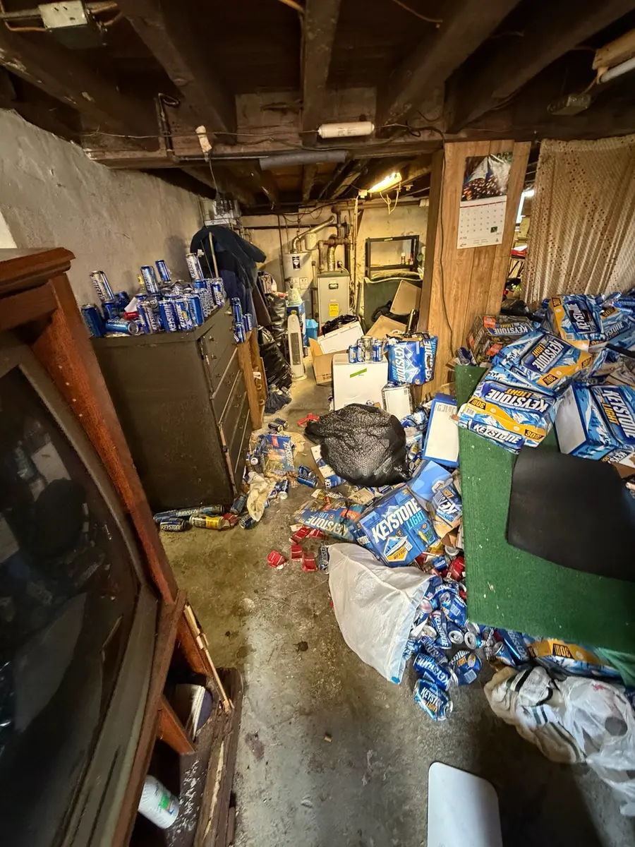 Basement filled with cans and unwanted items before the cleanout